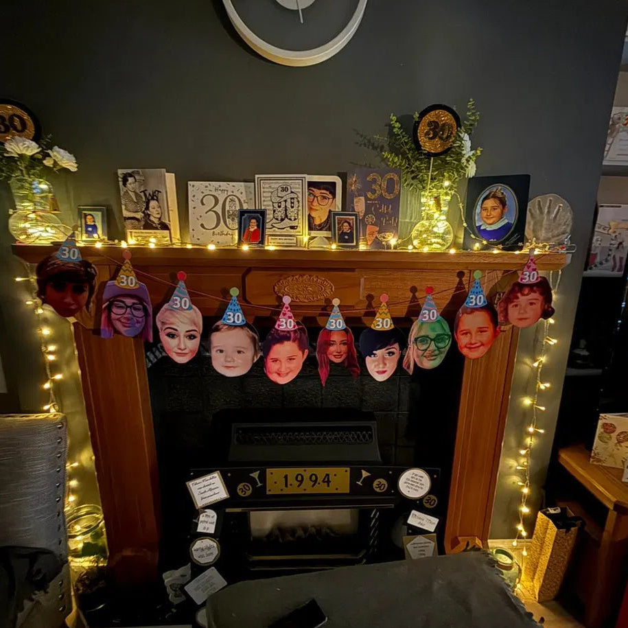 Personalised 30th birthday face bunting showing photo cut-outs of the birthday person through the years, wearing party hats and hanging on a fireplace.
