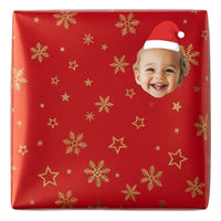 Red gift box with gold snowflakes and stars, featuring a child's face and Santa hat. Personalised Santa Hat Gift Label Sticker
