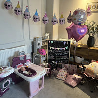 Custom toddler face photo bunting with party hats and sunglasses hanging above a playroom set up for a girl's 2nd birthday party.