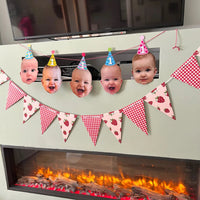 Personalised baby face photo bunting with birthday party hats hanging above a fireplace for a 1st birthday party.